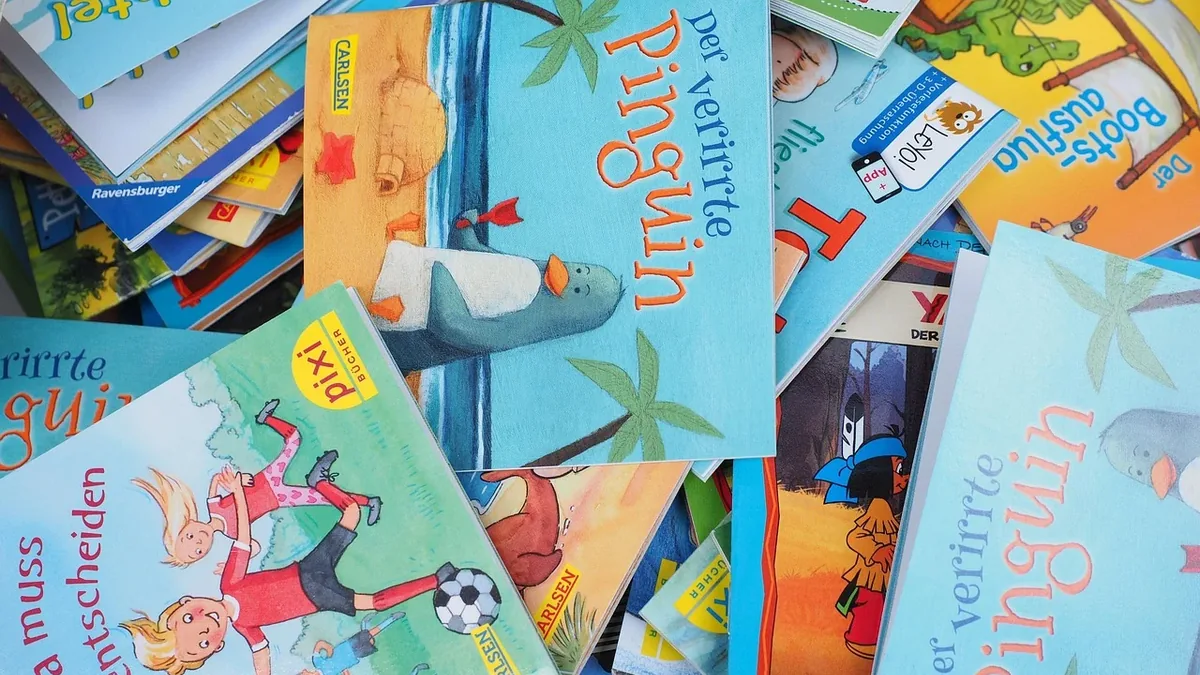 A pile of children's books in various languages, including German, with some featuring colorful illustrations and others with text.