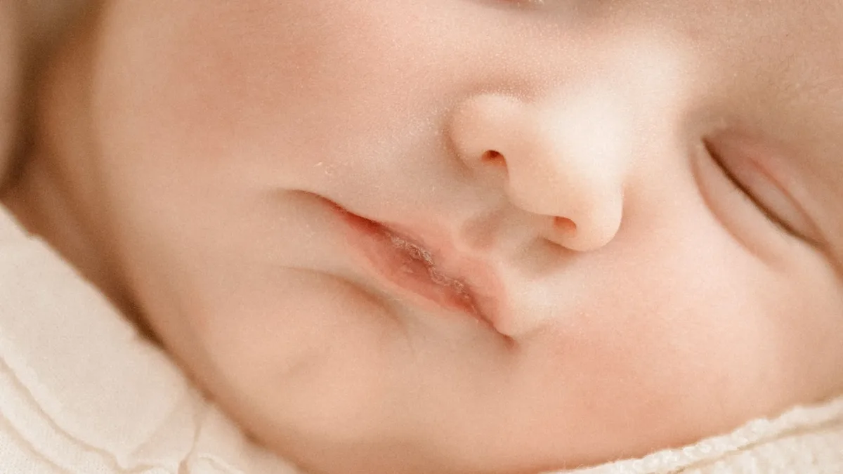 A close-up of a baby's face, with the baby's eyes closed and mouth slightly open.