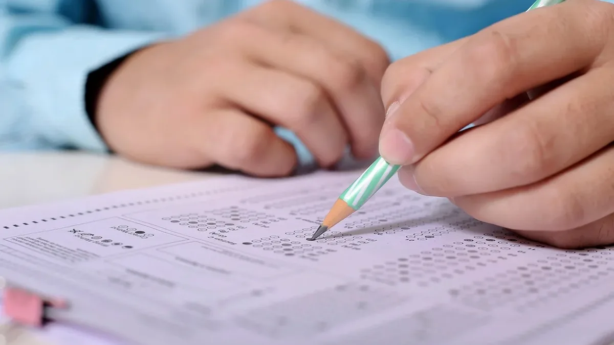 A person's hands holding a pencil over a multiple-choice test.